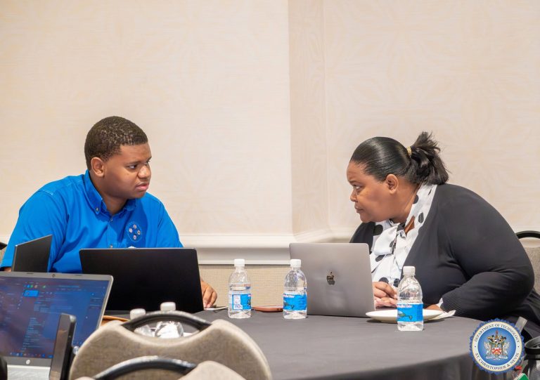 Two participants reviewing their work on laptops at the cybersecurity workshop in St. Kitts, October 2026